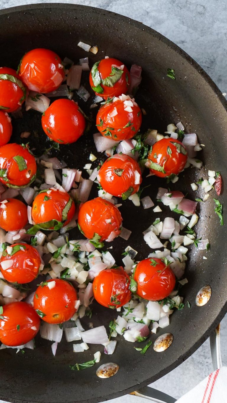burst cherry tomatoes in a pan with shallots