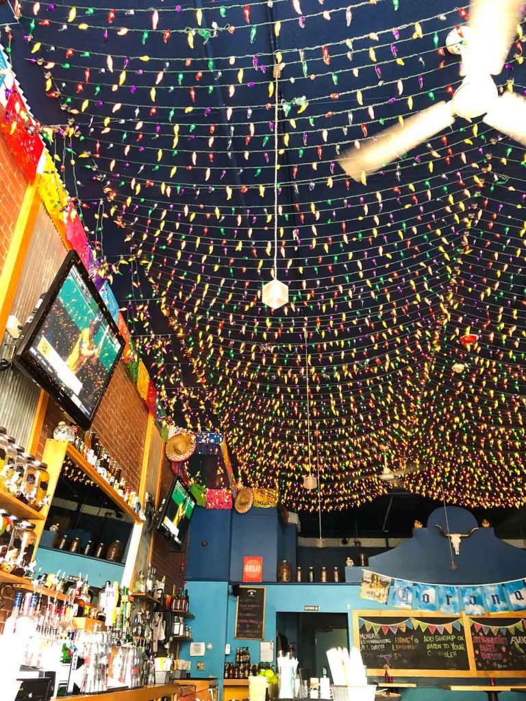 a restaurant with colorful string lights hanging from the ceiling