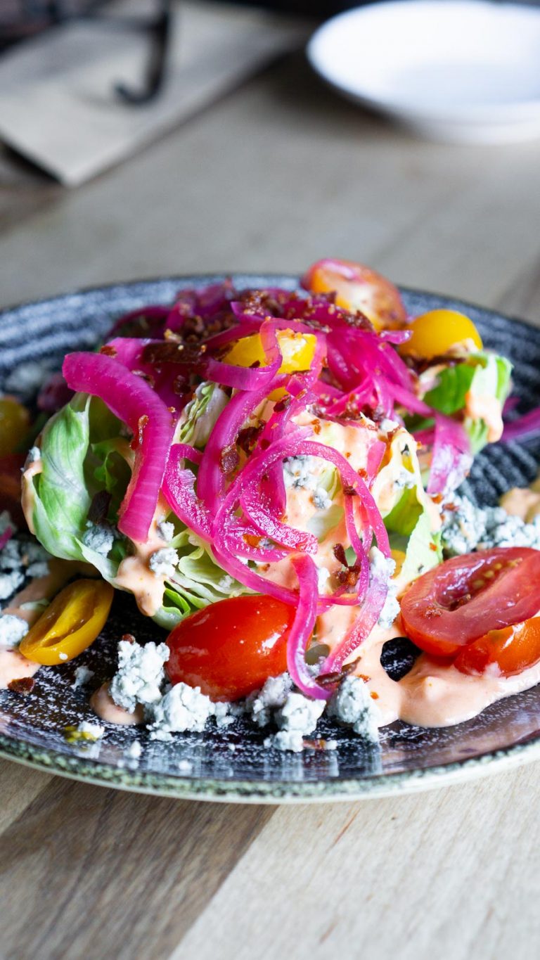 wedge salad with pickled onions, tomatoes, and blue cheese