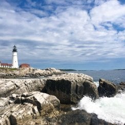 landscape photo of the portland head lighthouse with waves crashing on rocks