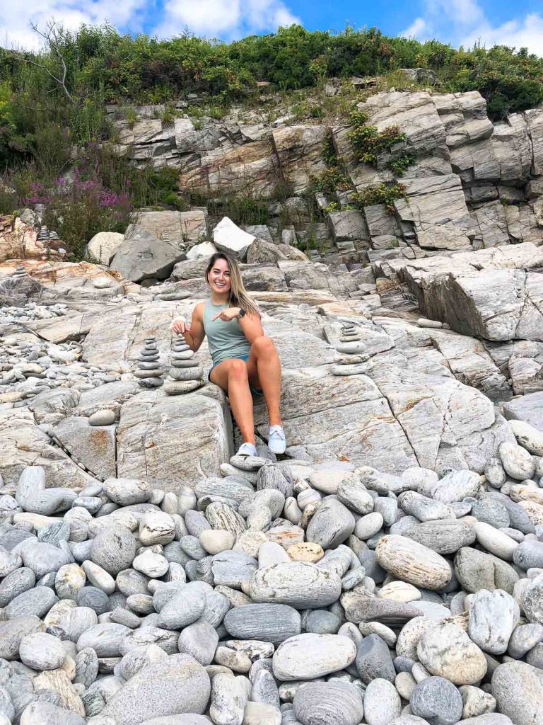 a girl sitting on rocks at fort williams park