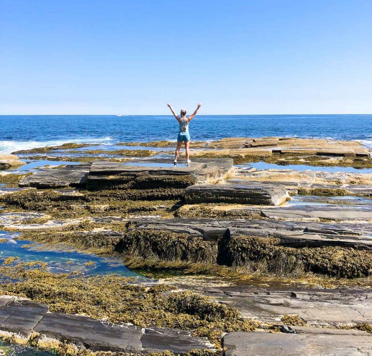 girl standing on rocks overlooking the ocean in portland maine