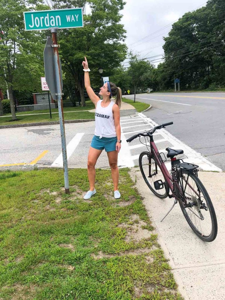 a girl standing next to a bike and pointing at a street sign