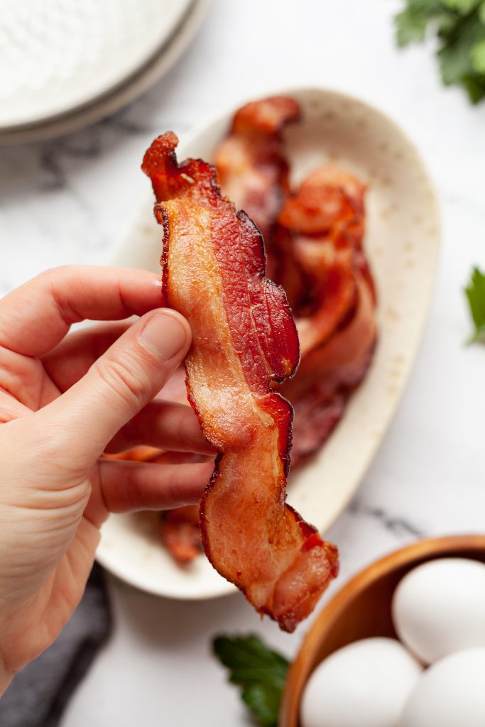 hand holding a piece of air fryer bacon