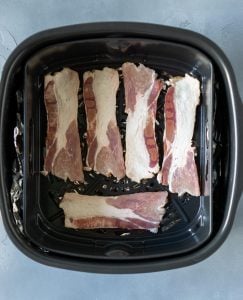 bacon strips in a black air fryer basket