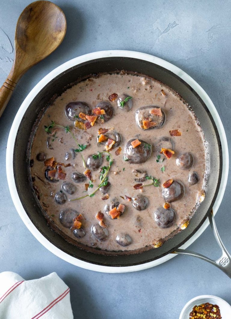 mushroom bacon gravy in a pan with a wooden spoon