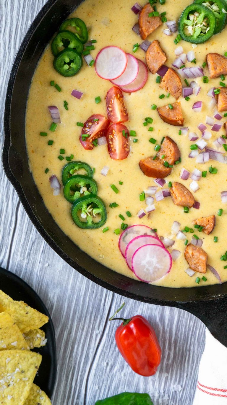 beer cheese dip in a cast iron skillet with chips and peppers