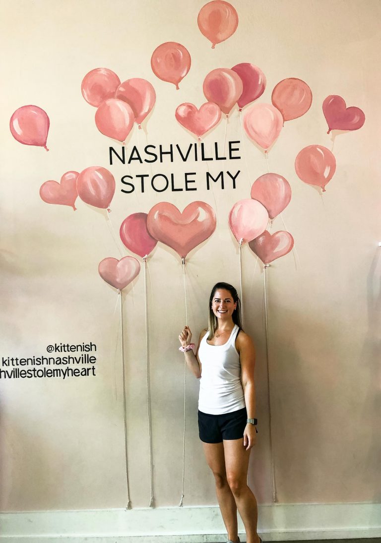 a girl standing in front of a mural with heart balloons