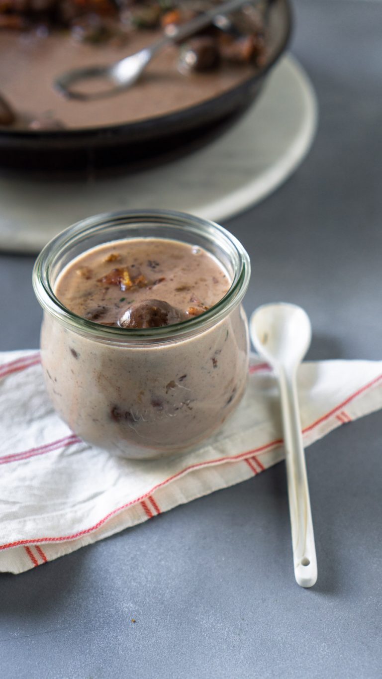 bacon gravy in a small glass jar and a white spoon