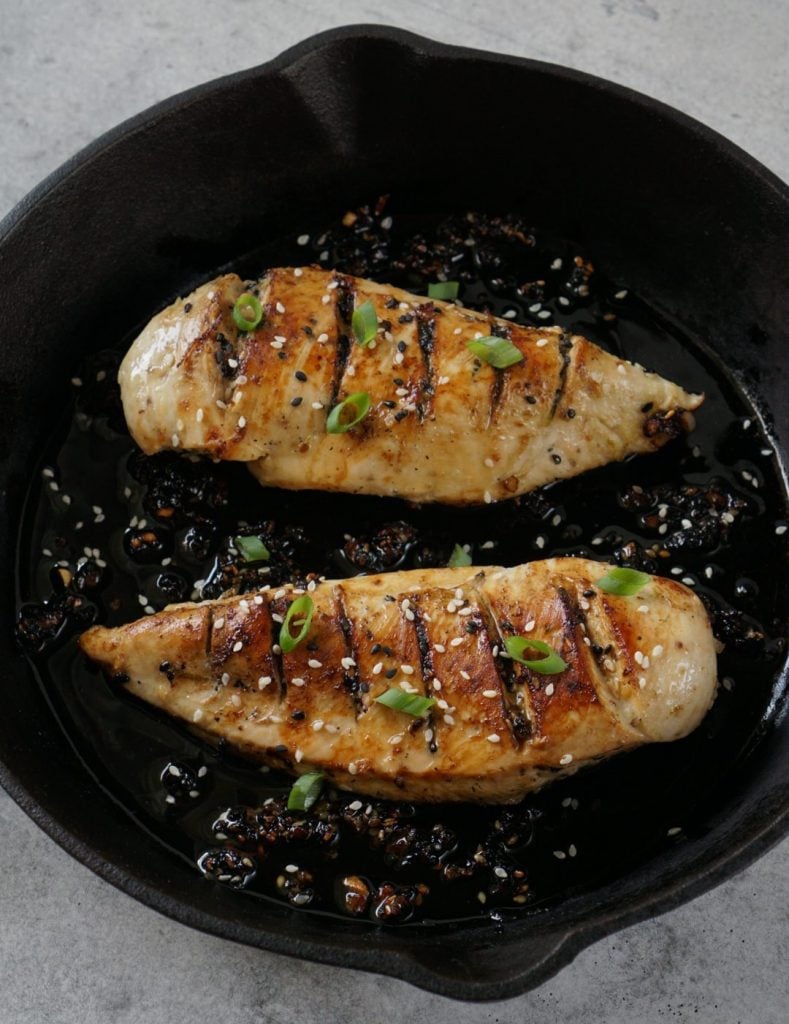 two chicken breasts marinated in a cast iron pan