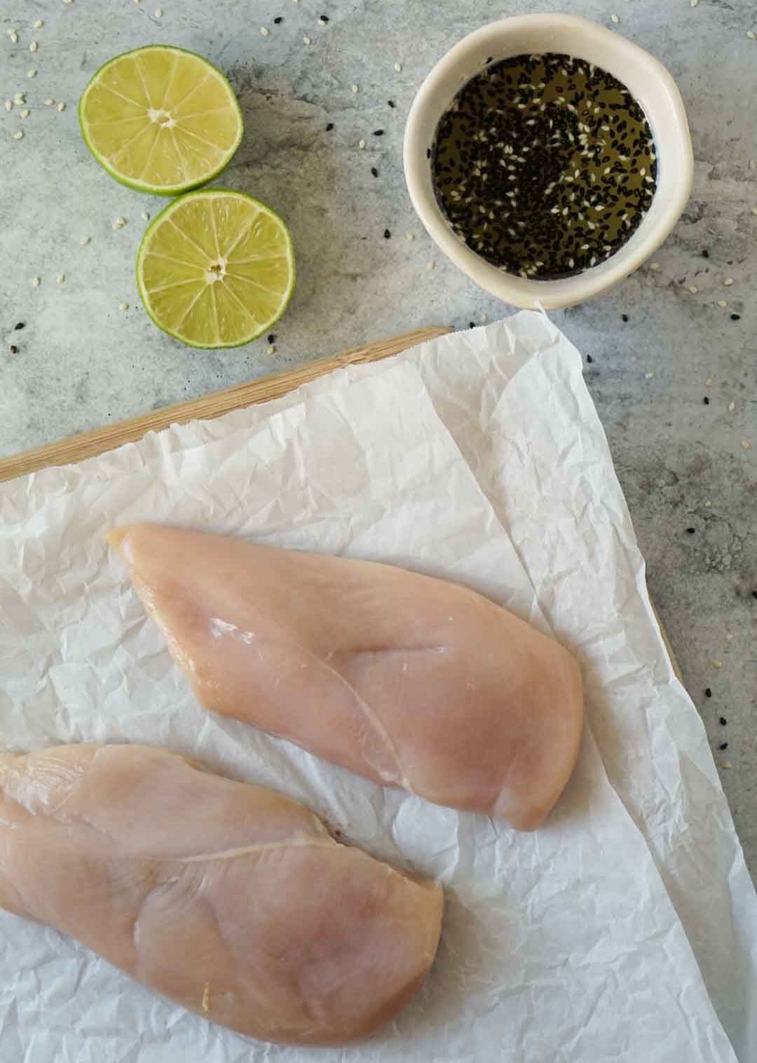 raw chicken, sesame ginger lime marinade, and a lime cut in half