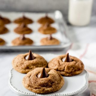 3 snickerdoodle hershey kiss cookies on a white cake stand