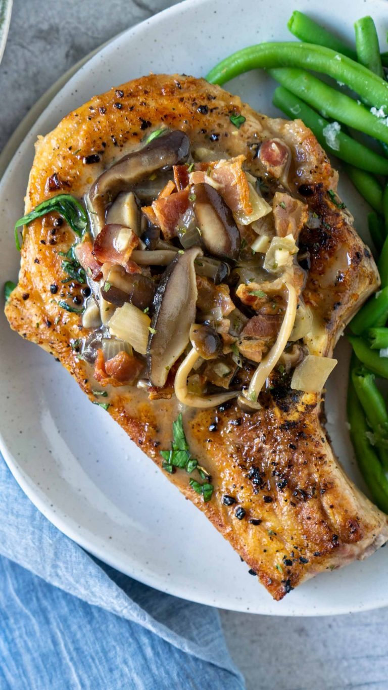 a pork chop with green beans on a white plate