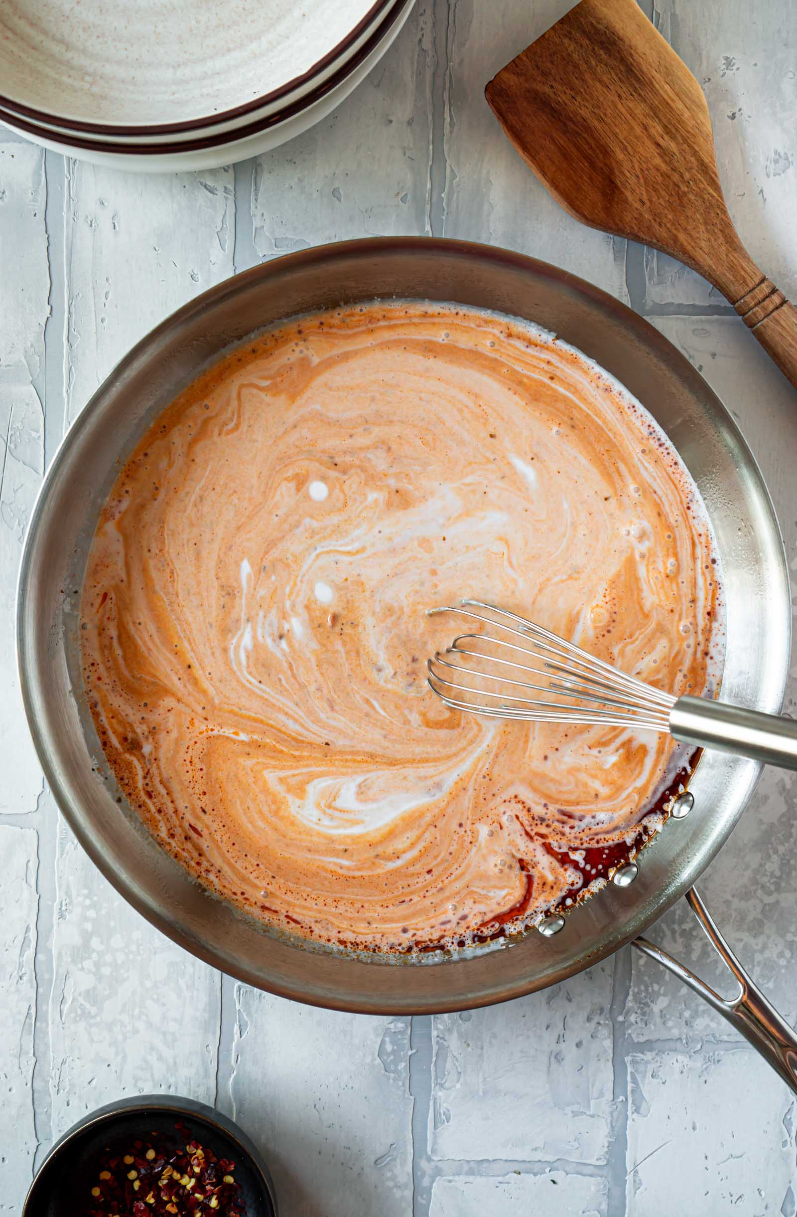 a whisk combining the ingredients for the pesto cream sauce