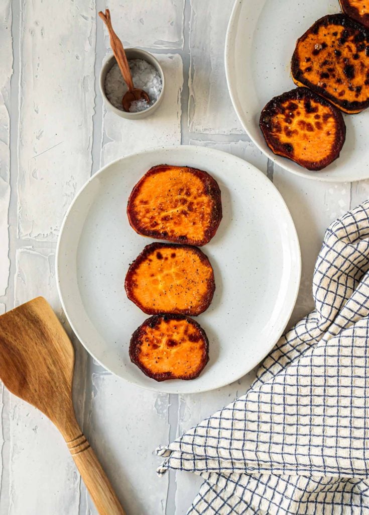 sliced and toasted sweet potato rounds on a grey plate