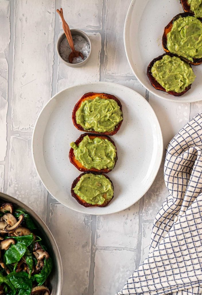 guacamole on sweet potato rounds and a pan of spinach and mushrooms