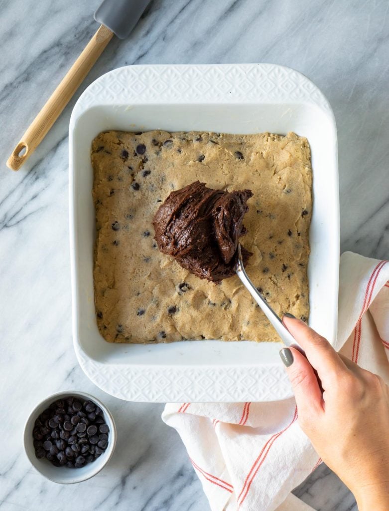 a spoon spreading melted chocolate over cookie dough