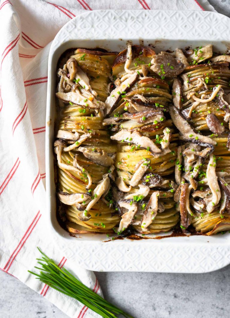 hasselback potato gratin in a white baking dish with chives