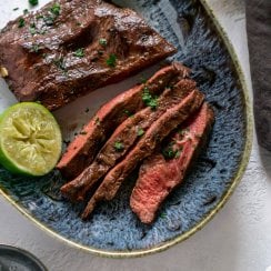 air fryer steak sliced on a blue plate with limes