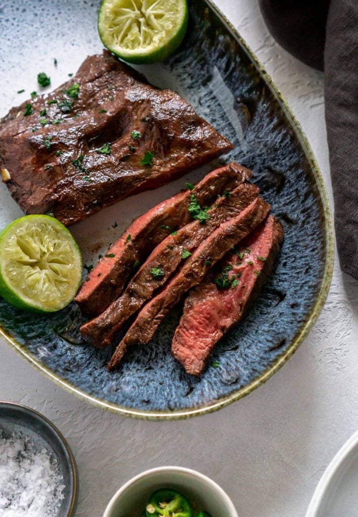 air fryer steak sliced on a blue plate with limes