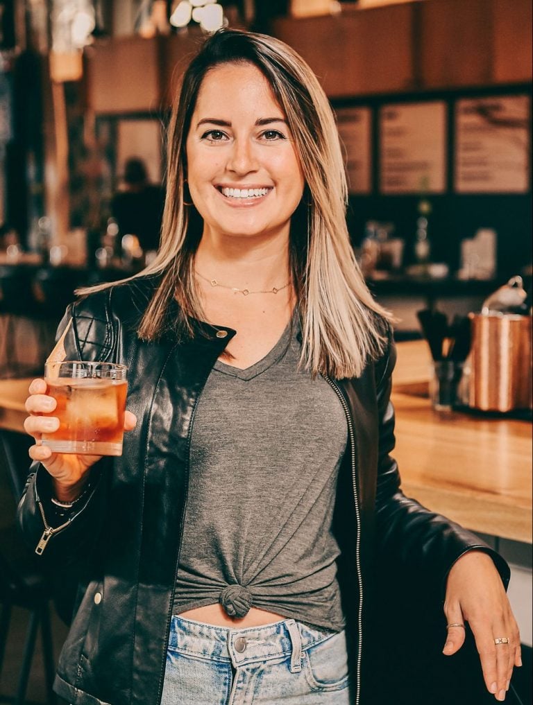 Jordan holding a cocktail next to a bar