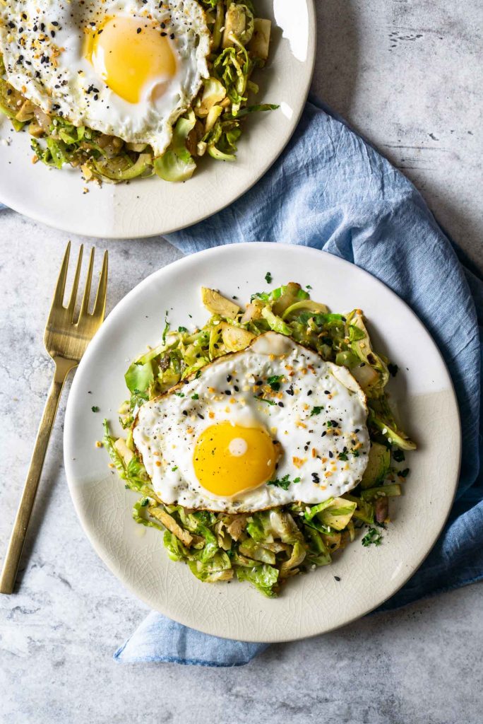 brussels sprouts hash with a fried egg on a plate and a blue napkin