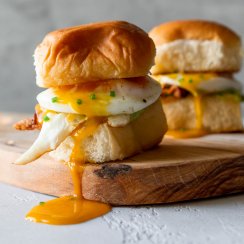 two breakfast sandwich sliders on a wood board