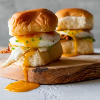 two breakfast sandwich sliders on a wood board