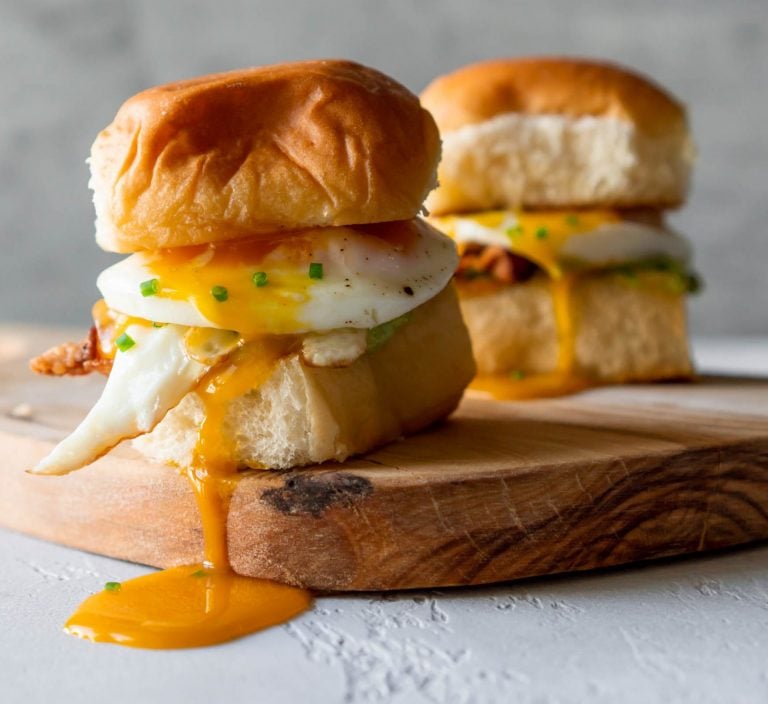 two breakfast sandwich sliders on a wood board