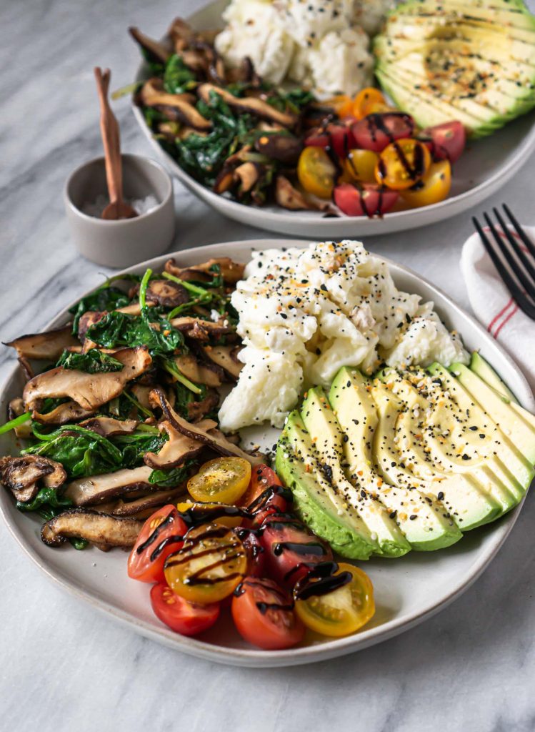 scrambled eggs, avocado, tomatoes, and mushrooms on a plate