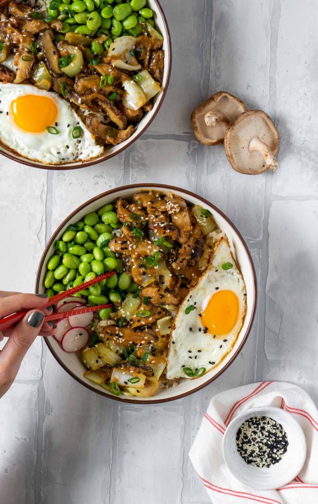 a hand taking a bite out of the bowl with chopsticks