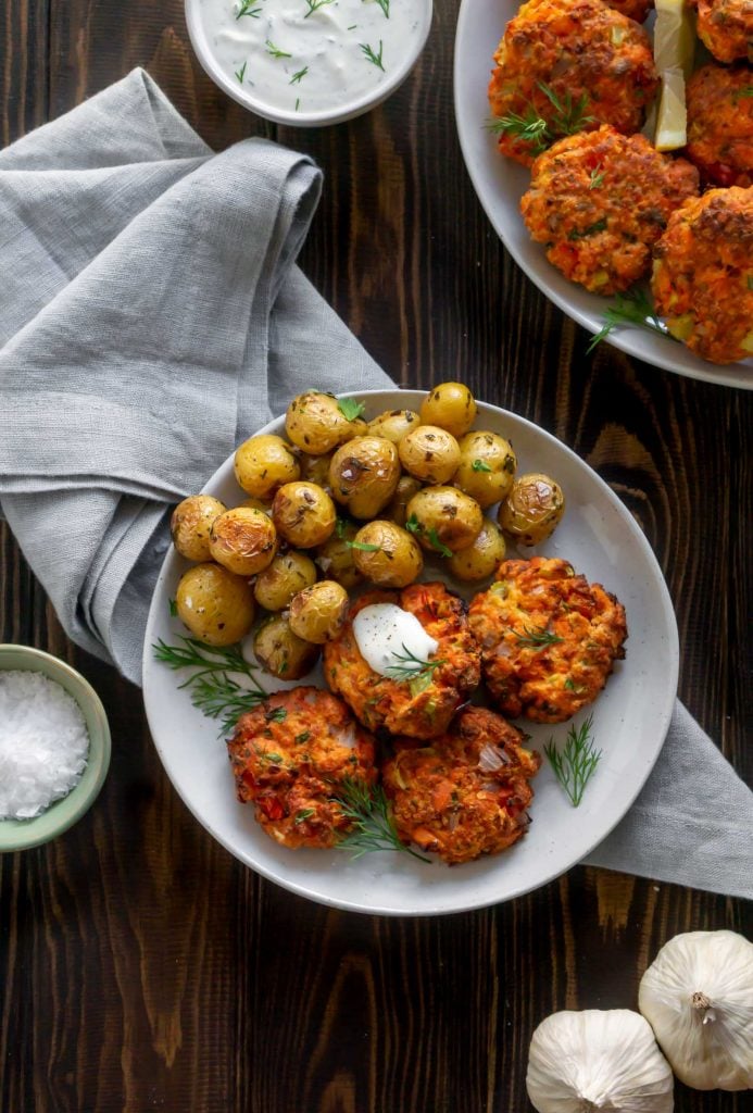 overhead photo of salmon patties on a white plate with roasted potatoes