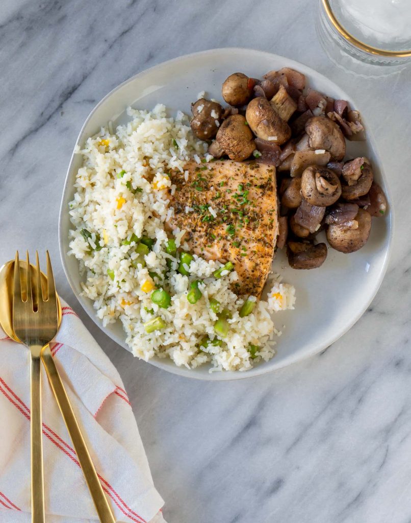 salmon, rice, and mushrooms on a plate with a gold fork