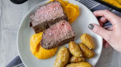 steak, butternut squash mash, and potatoes on a white plate