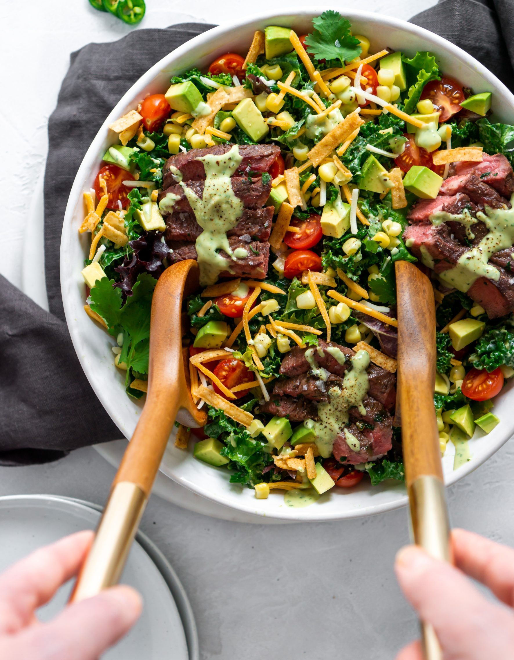 two hands holding salad tongs to serve