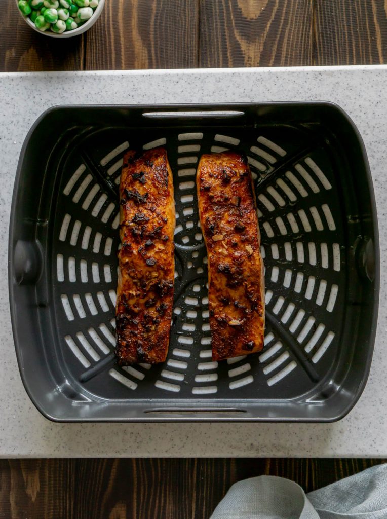 two salmon fillets in an air fryer basket