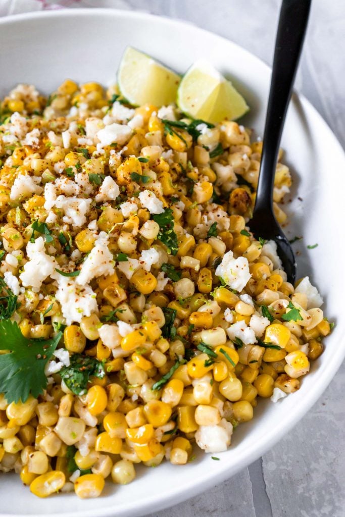 mexican street corn dip in a white bowl with a black fork
