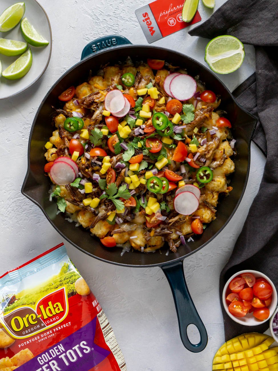 tater tot nachos in a skillet with ingredients around