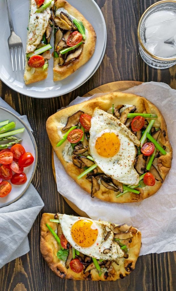 breakfast pizza on parchment paper and on a plate with a glass of water