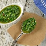chimichurri sauce in a white serving dish and on a silver spoon