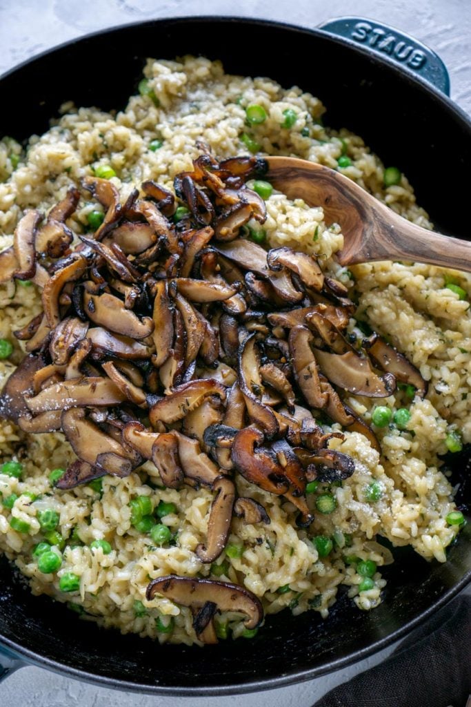 mushroom risotto in a skillet with a wooden spoon