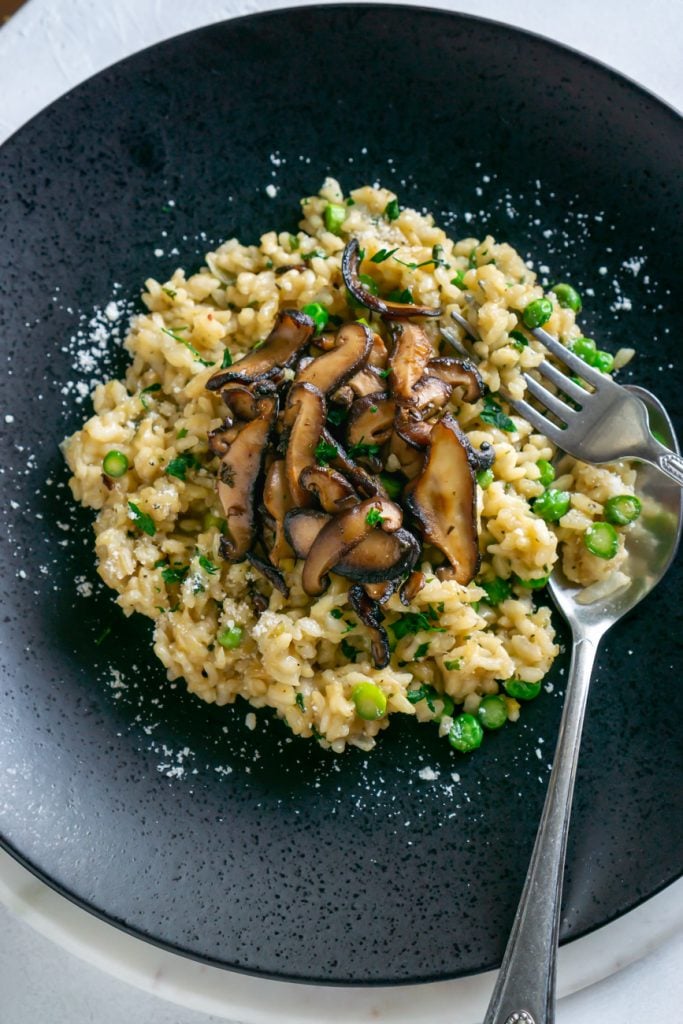 mushroom risotto on a black plate with a fork