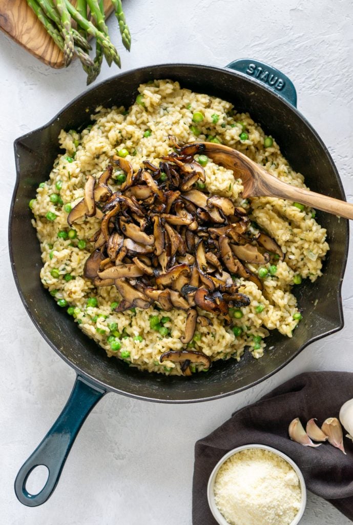 mushroom risotto in a staub skillet with wooden spoon