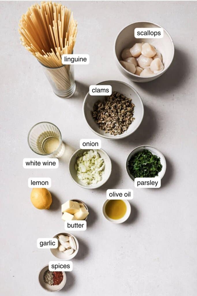 linguine, clams, lemon, scallops, spices, olive oil, parsley, onion, and garlic in small ingredient bowls