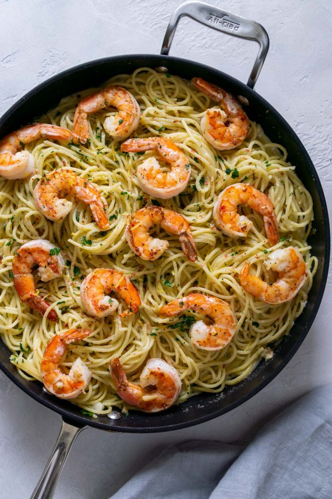 pasta in a large black pan with jumbo shrimp on top