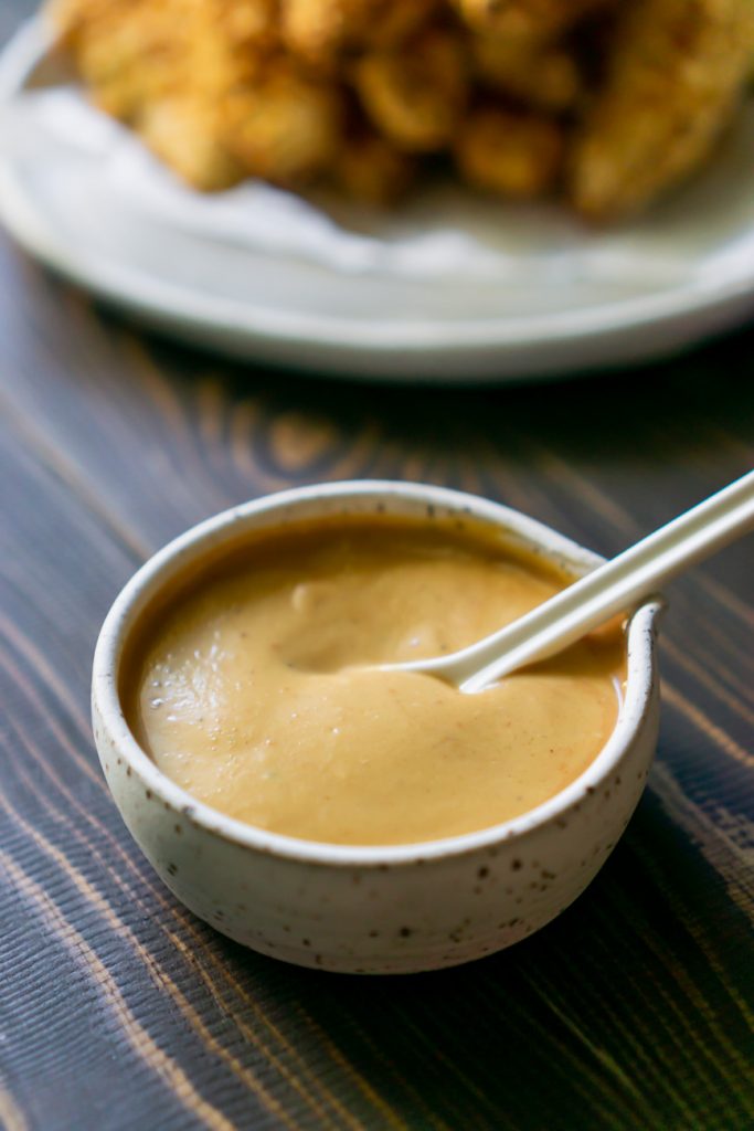 chik fil a sauce in a bowl and chicken tenders on a plate in the background