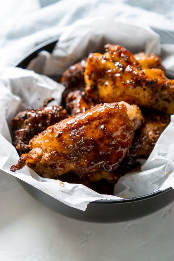 air fryer old bay wings in a black bowl with white parchment paper