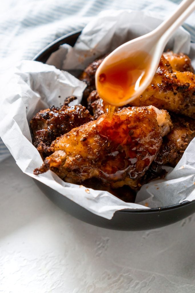 spoon drizzling hot honey on old bay wings
