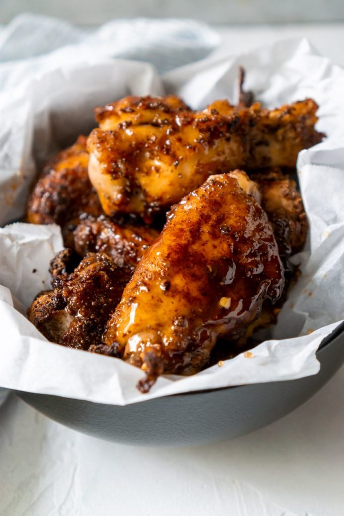 honey old bay wings in a black bowl with white parchment paper