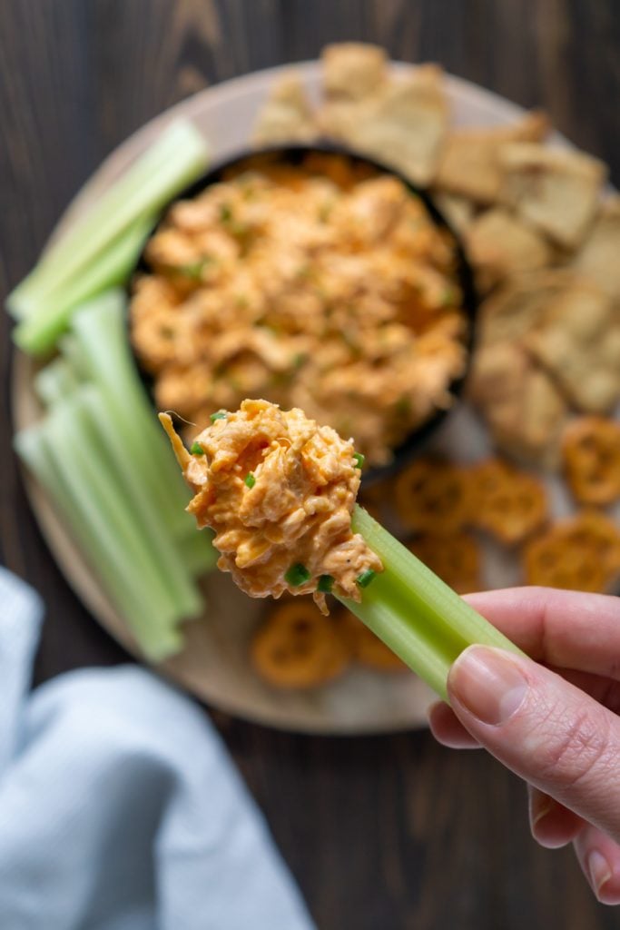hand holding celery dipped in slow cooker buffalo chicken dip